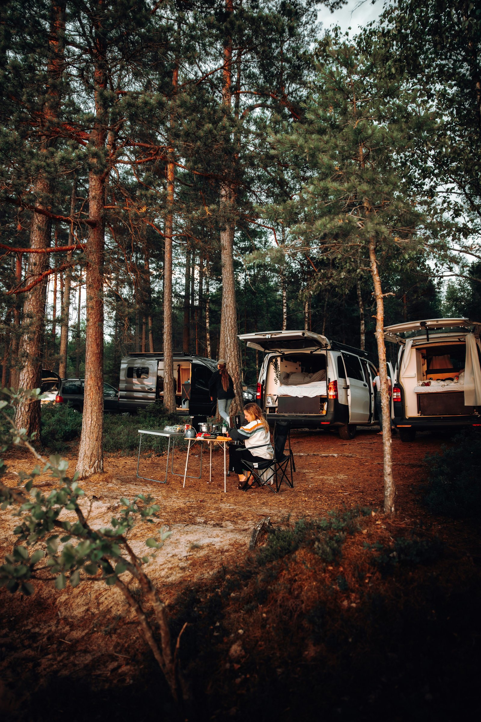 RV campers gathered in a wooded campground near their rigs
